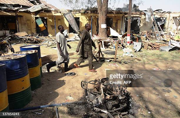 Two residents pass by bombed corner shops attached to Bompai police barracks in the northern Nigerian city of Kano on January 24 after multiple...