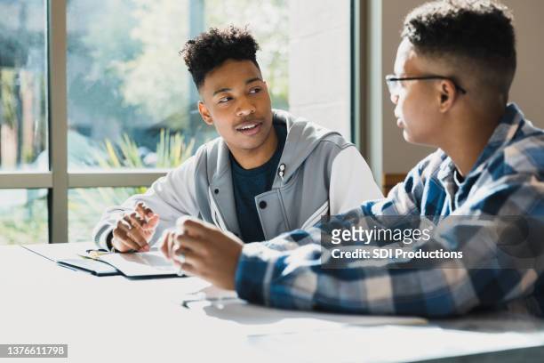 zwei männliche teenager-freunde sprechen während des unterrichts miteinander - friendship males stock-fotos und bilder