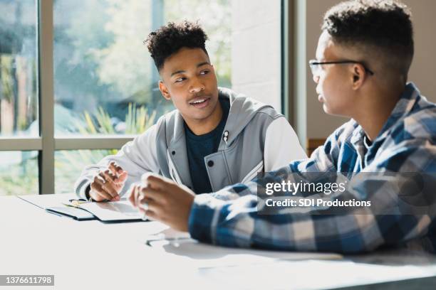 two male teenage friends talk together during class - black boy stockfoto's en -beelden