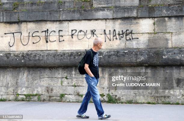 Pedestrian walks past graffiti which reads as 'justice for Nahel' on a wall at Place de la Concorde in Paris on July 1 after continued protests...