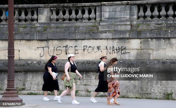 Pedestrians walk past graffiti which reads as 'justice for Nahel' on a wall at Place de la Concorde in Paris on July 1 after continued protests...