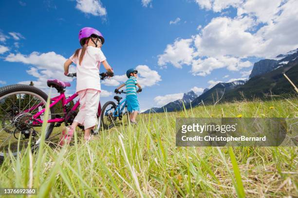 sibling walking their bike up the hill - canmore stock pictures, royalty-free photos & images