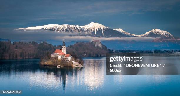 scenic view of lake by snowcapped mountain against sky,bleder see,bled,slovenia - slovenia winter stock pictures, royalty-free photos & images