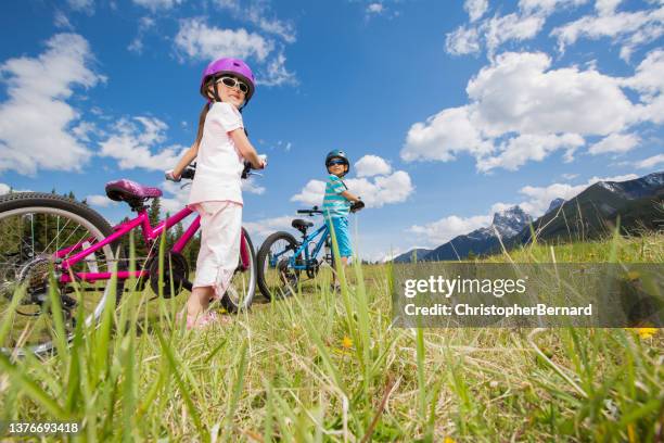 sibling walking their bike up the hill - canmore stockfoto's en -beelden