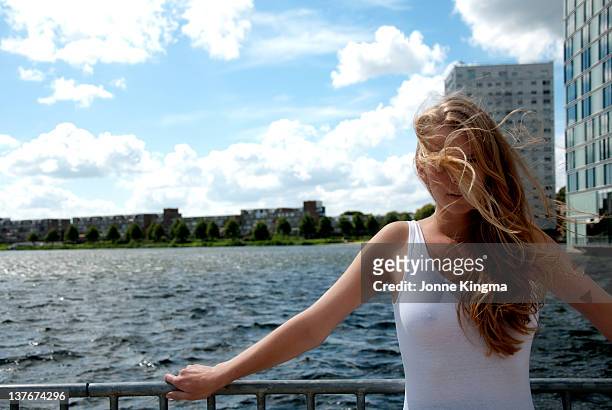 young woman leaning on railing by sea - almere stockfoto's en -beelden