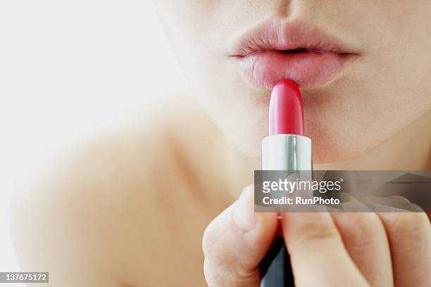 young woman applying lipstick - woman applying makeup stock-fotos und bilder