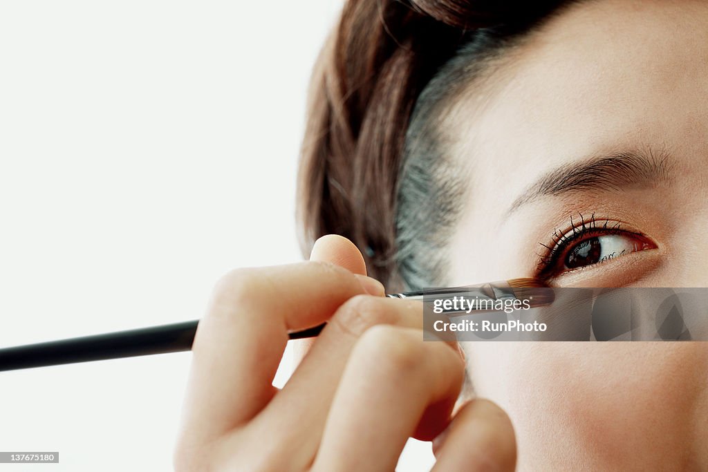 Young woman putting on make-up,close-up