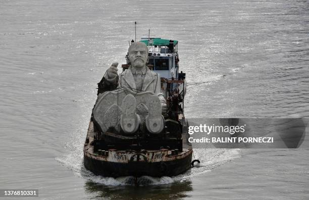 Monumental sculpture of Russian revolutionary and communist politician Vladimir Ilyich Lenin passes under Chain bridge as it is transported along the...