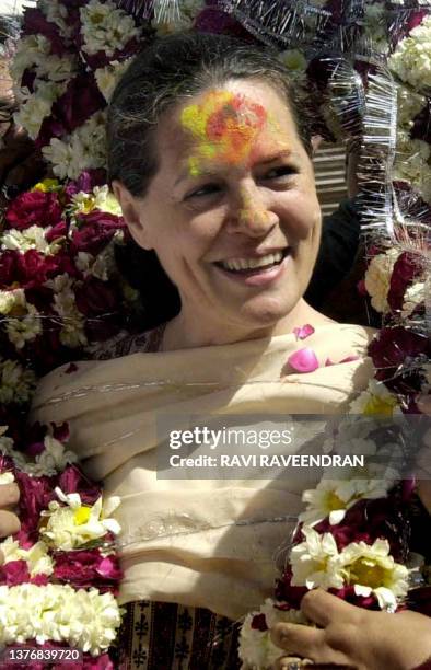 Indian Opposition leader and Congress Party President Sonia Gandhi smiles as she wears a garland and coloured powder on her forehead during...