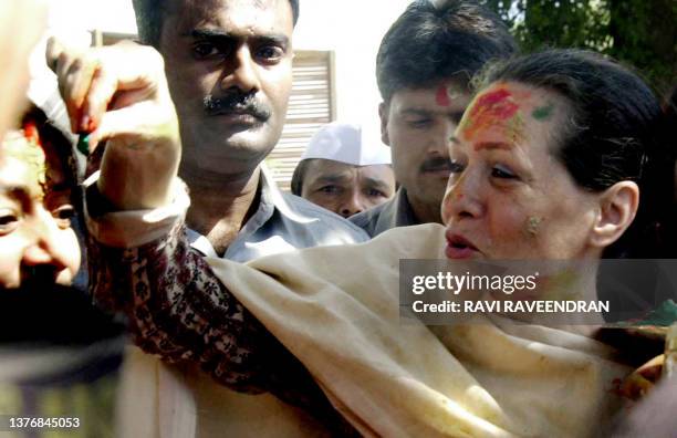 Indian Opposition leader and Congress Party President Sonia Gandhi places a dot of coloured powder on a supporters forehead as she sports coloured...
