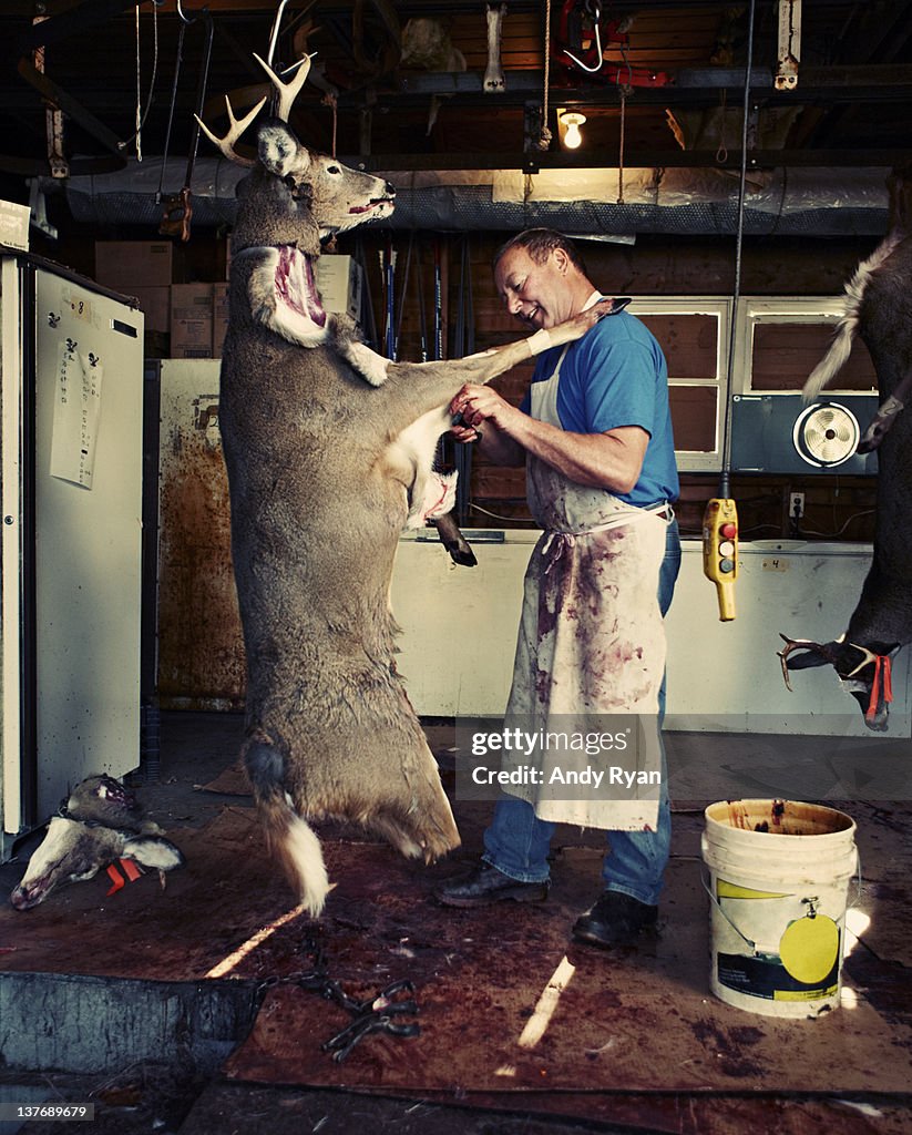 Man butchering deer in garage.