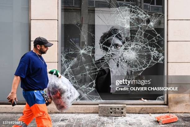 Municipal employee works in front of a looted shop following a fourth consecutive night of rioting in France sparked by the death of teenage driver...