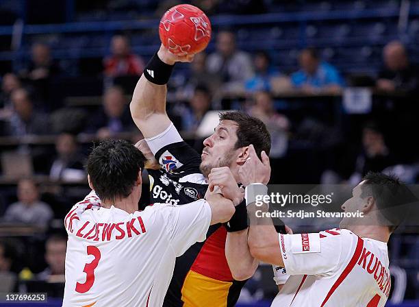 Michael Haas of Germany vies with Patryk Kuchczynski and Krzysztof Lijewski of Poland during the Men's European Handball Championship 2012 second...