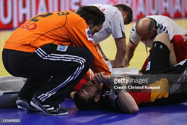 Silvio Heinevetter cares of the injured Michael Haass of Germany during the Men's European Handball Championship second round group one match between...