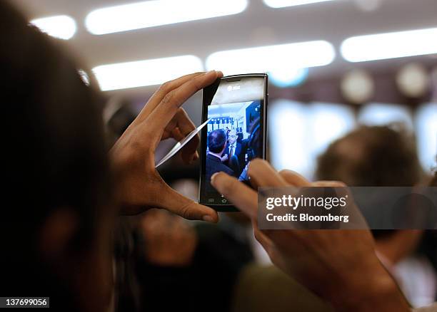 An attendee uses a mobile phone to take a photograph of Meles Zenawi, Ethiopia's prime minister, at the Congress Center during day one of the World...