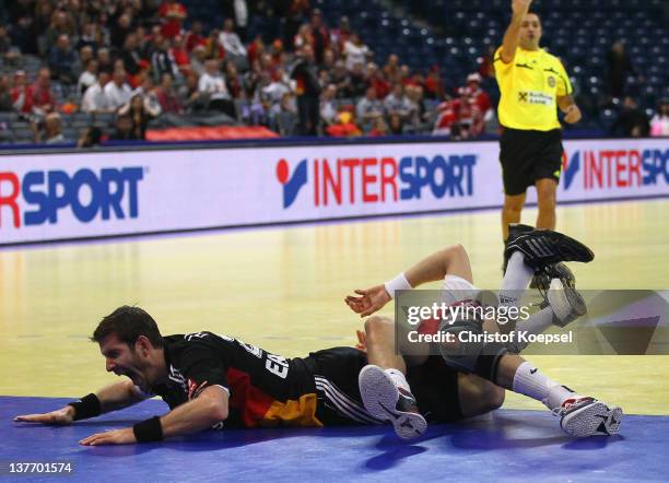 Michael Haass of Germany falls over Krzysztof Lijewski of Poland during the Men's European Handball Championship second round group one match between...