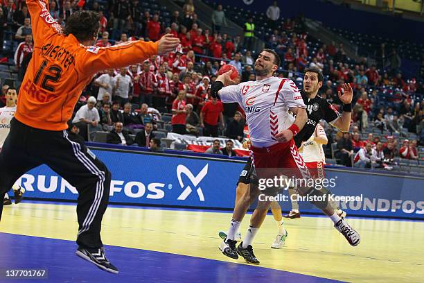 Bartosz Jurecki of Poland scores a goal Silvio Heinevetter of Germany and Michael Haass of Germany during the Men's European Handball Championship...