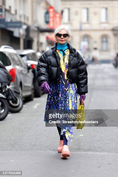 Influencer Grece Ghanem wearing a black puffer jacket by Prada, a long multicolored floral print dress by Balenciaga, a blue vintage turtleneck...
