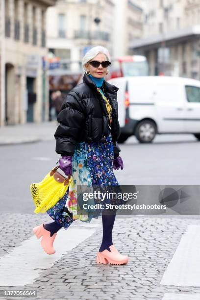 Influencer Grece Ghanem wearing a black puffer jacket by Prada, a long multicolored floral print dress by Balenciaga, a blue vintage turtleneck...