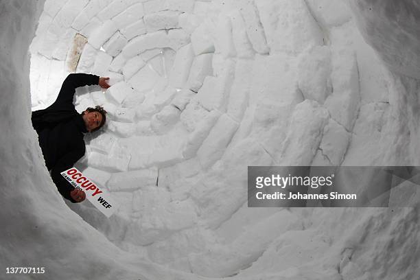 An occupy protester poses with a placard reading "Occupy WEF" inside an igloo built at the protesters' encampment on January 25, 2012 in Davos,...