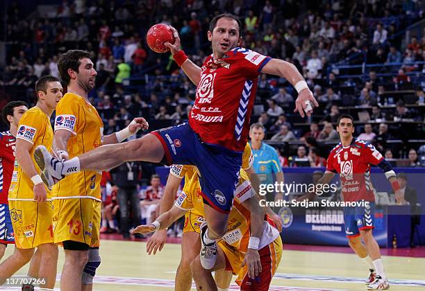 Alem Toskic of Serbia jumps to score past Filip Mirkulovski of Macedonia during the Men's European Handball Championship 2012 second round group one,...