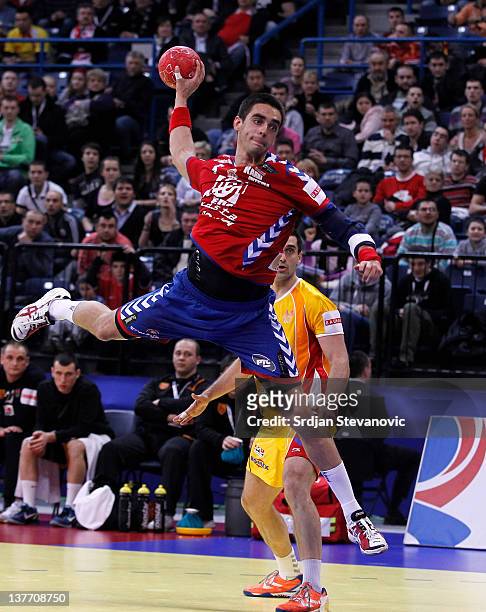 Zarko Sesum of Serbia jumps to score past Kiril Lazarov of Macedonia during the Men's European Handball Championship 2012 second round group one,...