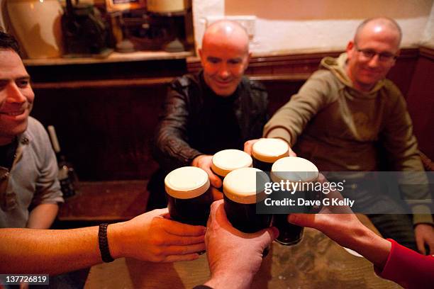 men holding glasses of stout - irish pub fotografías e imágenes de stock