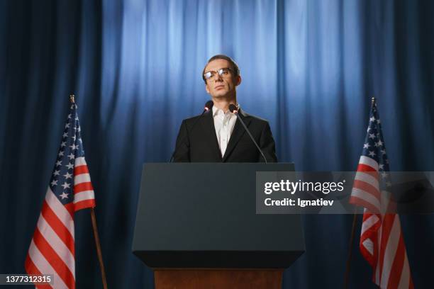 visione a bassa angolazione del giovane politico americano serio che distoglie lo sguardo durante il suo discorso ai dibattiti - envoy foto e immagini stock