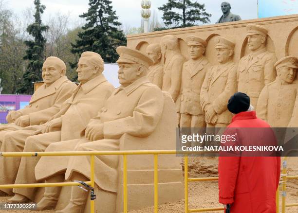 Russian woman stands near a sand sculpture of former British Prime Minister Winston Churchill, US President Franklin D. Roosevelt and Soviet dictator...