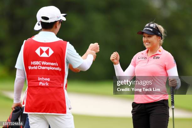 Brooke Henderson of Canada bumps fists with Gi Hyeob Nam, caddie and husband of Inbee Park of South Korea, on the 18th green after finishing the...