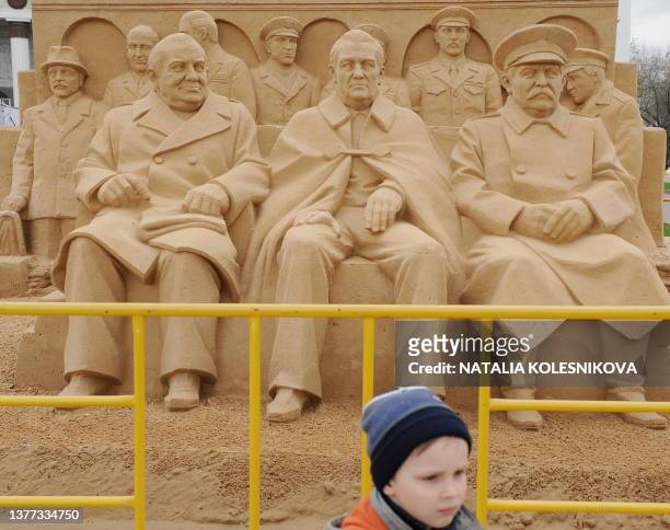 Russian boy stands near a sand sculpture of former British Prime Minister Winston Churchill, US President Franklin D. Roosevelt and Soviet dictator...