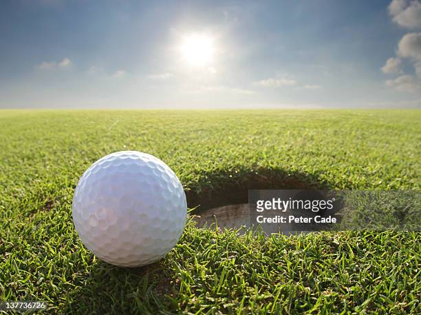 golf ball by hole - effortless stock-fotos und bilder
