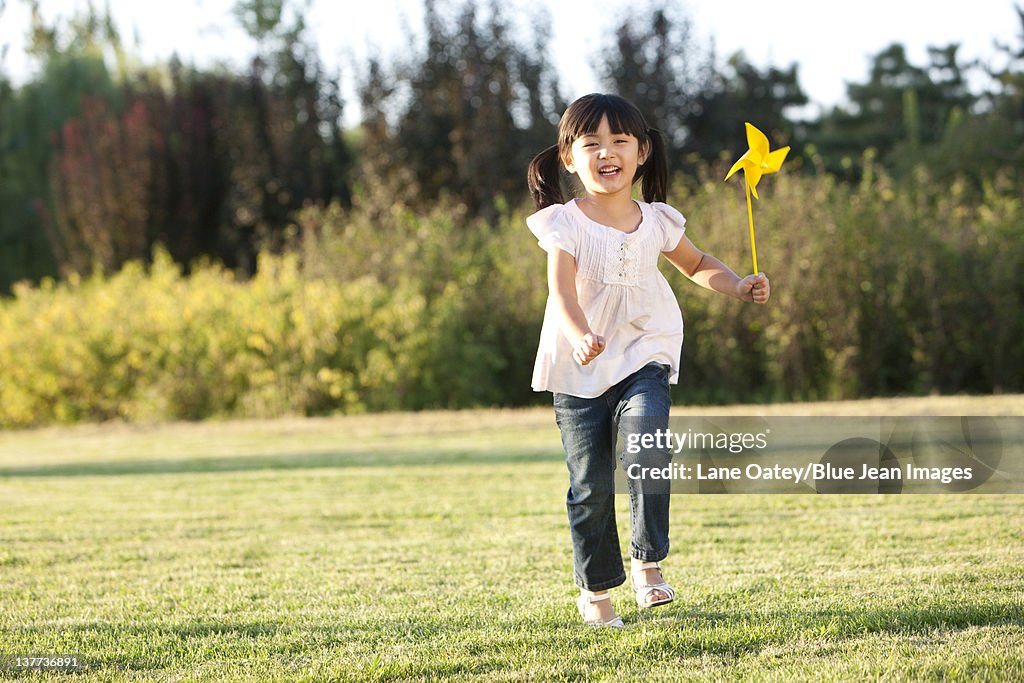 Young girl playing in a field with a pinwheel