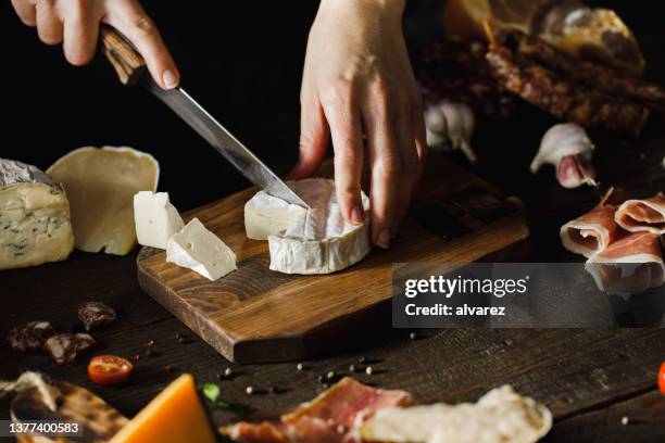 mujer cortando a mano camembert en tabla de madera - queso de cabra fotografías e imágenes de stock