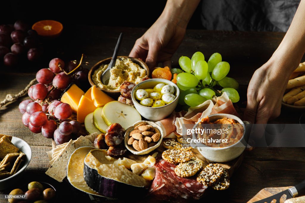 Close-up of a woman serving cheese and meat platter