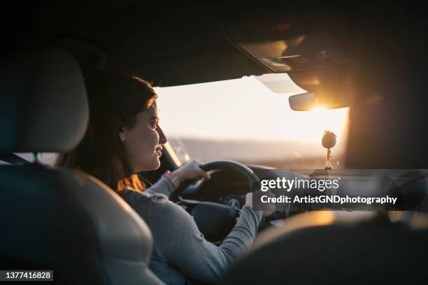 junge frau, die bei sonnenuntergang auto fährt. - steuern stock-fotos und bilder