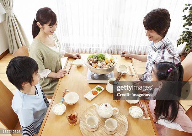 parents and kids sitting around japanese hot pot - mizutaki stockfoto's en -beelden