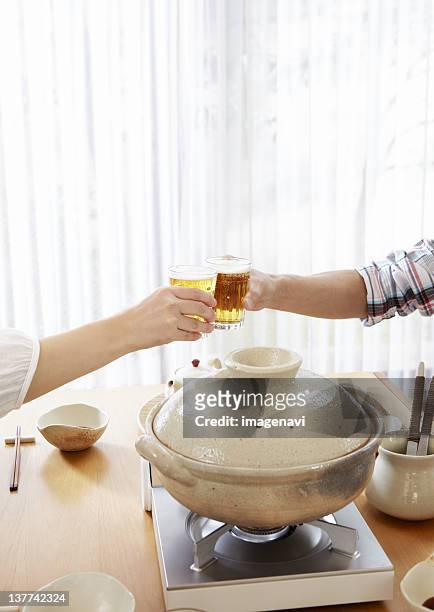 couple's hands having a toast with beer - mizutaki stock pictures, royalty-free photos & images