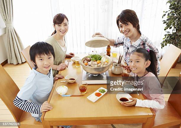 parents and kids sitting around japanese hot pot - mizutaki stockfoto's en -beelden