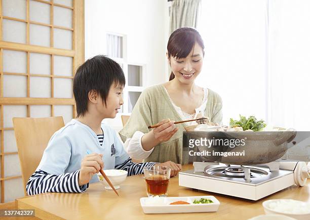 mother and son sitting around japanese hot pot - mizutaki stockfoto's en -beelden