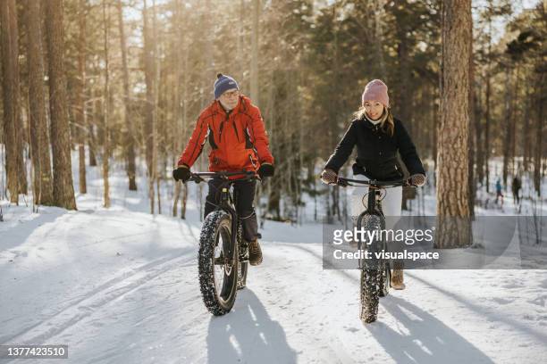 father and daughter fatbiking in nature - senior winter sport stock pictures, royalty-free photos & images