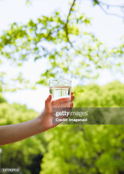 child's hand holding glass - glass of water hand ストックフォトと画像