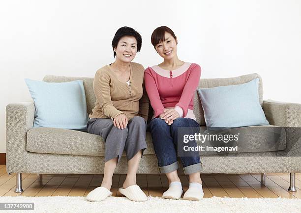 mother and daughter sitting on sofa - knitted house stock pictures, royalty-free photos & images