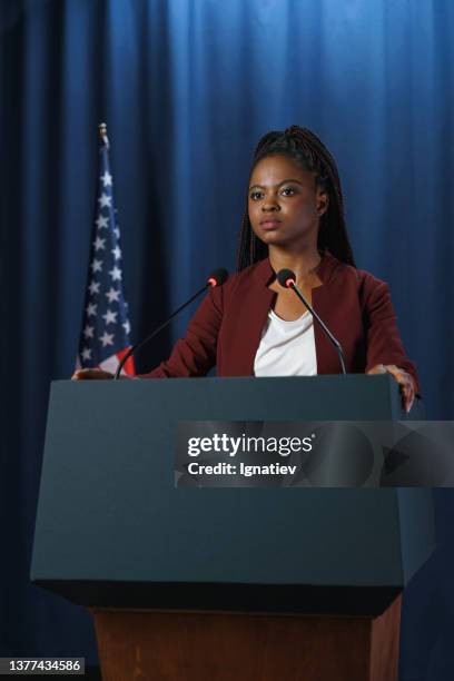 young african - american female politician in a red suit at the debates with serious face - mayor office stock pictures, royalty-free photos & images