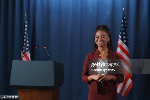 charming dark-skinned politician in a red suit posing on camera before  the speech with a smile - black politician stock pictures, royalty-free photos & images