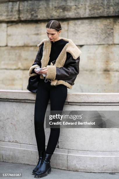 Guest wears a black pullover, a black shiny leather with white latte sheep interior / large collar oversized jacket, a black shiny leather handbag,...