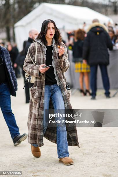 Guest wears a black t-shirt, a pale gray hoodie sweater, blue denim flared pants, a brown and beige checkered print pattern long coat, a beige...