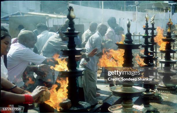 Devotees offer coconuts to fire after getting their heads shaved at Tirupati Tirumala, Andhra Pradesh.