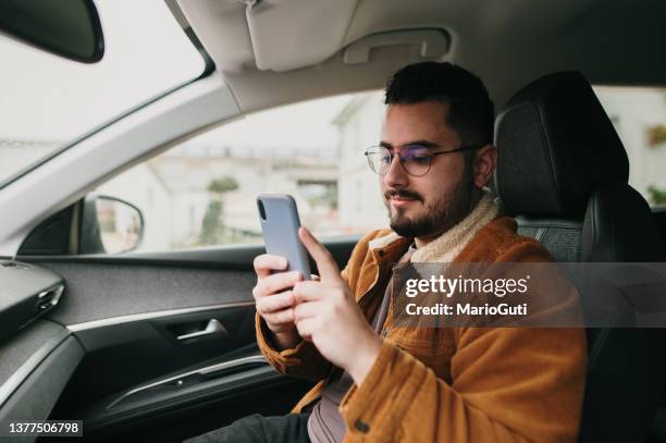 giovane uomo all'interno dell'auto usando uno smartphone - navigator foto e immagini stock