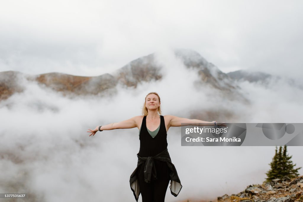 Canada, Whitehorse, Portrait of woman with arms outstretched in foggy landscape